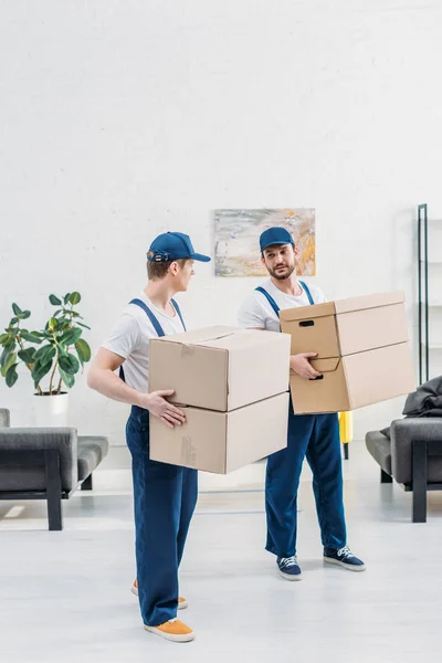 Dois Movers Uniforme Transportando Caixas Papelão Apartamento Com Espaço Cópia — Fotografia de Stock