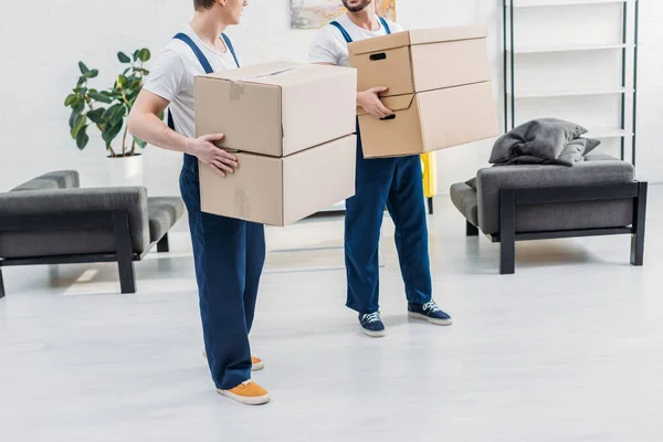 Cropped View Two Movers Uniform Carrying Cardboard Boxes Apartment — Stock Photo, Image