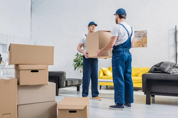 Two Movers Uniform Transporting Cardboard Box Living Room — Stock Photo, Image