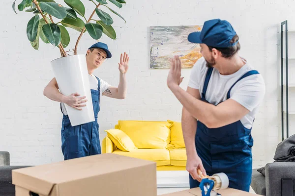 Mover Wrapping Cardboard Box Scotch Tape Waving Colleague Apartment — Stock Photo, Image