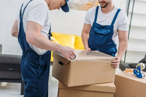 Cropped View Movers Wrapping Cardboard Box Stretch Film Apartment — Stock Photo, Image