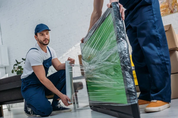 Two Movers Using Roll Stretch Film While Wrapping Green Screen — Stock Photo, Image