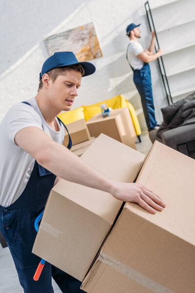 two movers transporting cardboard boxes and furniture in apartment