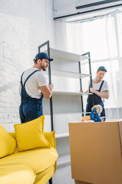 two movers in uniform transporting rack in apartment