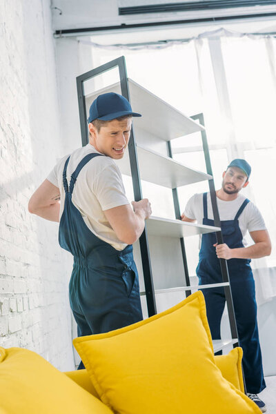 two movers in uniform transporting rack in apartment