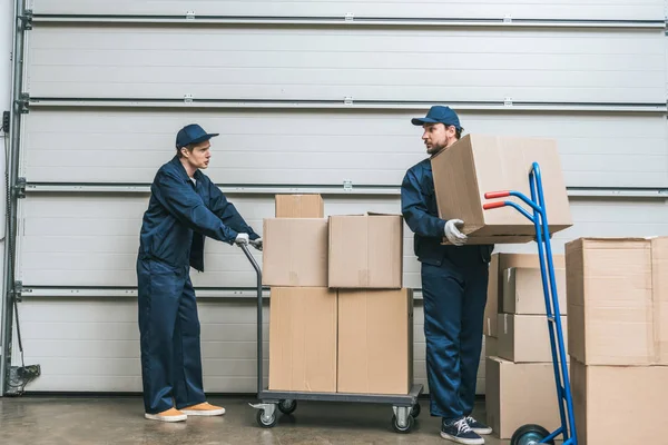 Two Movers Uniform Looking Each Other While Transporting Cardboard Boxes — Stock Photo, Image