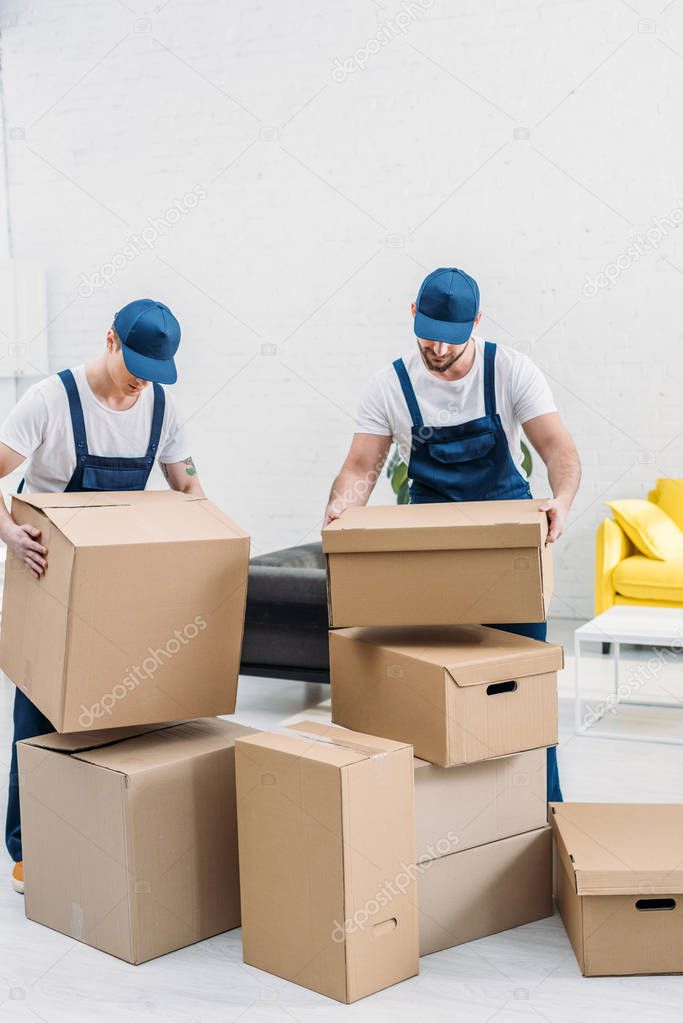 two movers transporting cardboard boxes in apartment