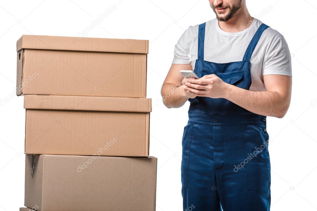 cropped view of mover with cardboard boxes using smartphone isolated on white
