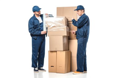 two movers wrapping cardboard boxes with roll of stretch film on white clipart