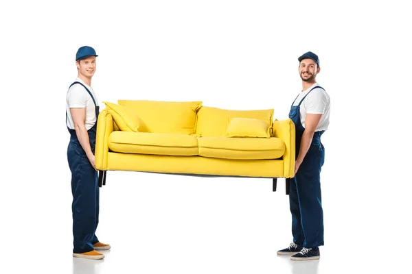Twee Lachende Verhuizers Vervoeren Gele Sofa Kijkend Naar Camera Wit — Stockfoto