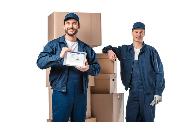 Two Smiling Movers Cardboard Boxes Presenting Digital Tablet Facebook App — Stock Photo, Image