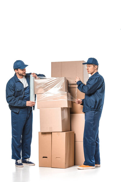 two movers wrapping cardboard boxes with roll of stretch film on white