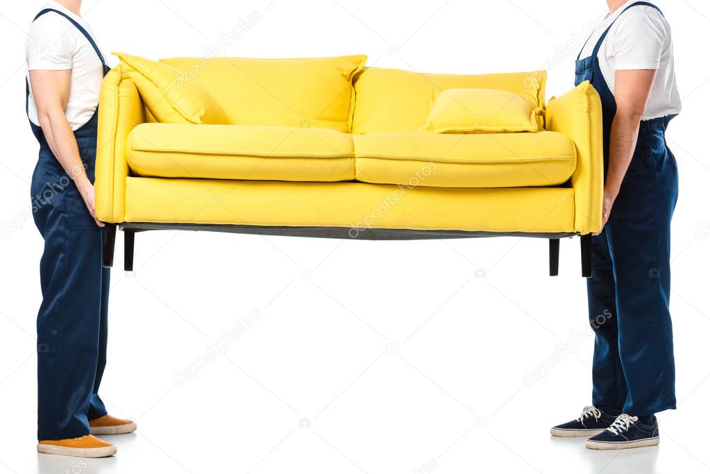 cropped view of two movers transporting yellow sofa on white