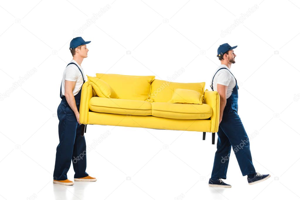side view of two movers transporting yellow sofa on white