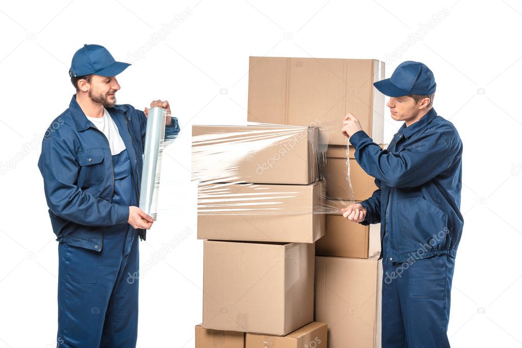 two movers wrapping cardboard boxes with roll of stretch film isolated on white