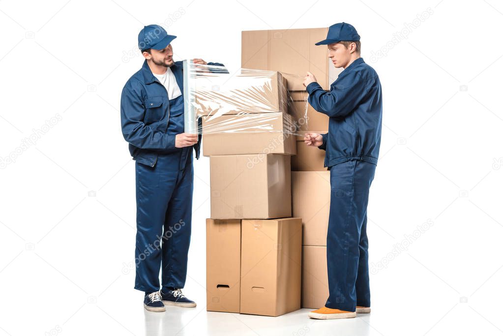 two movers wrapping cardboard boxes with roll of stretch film on white