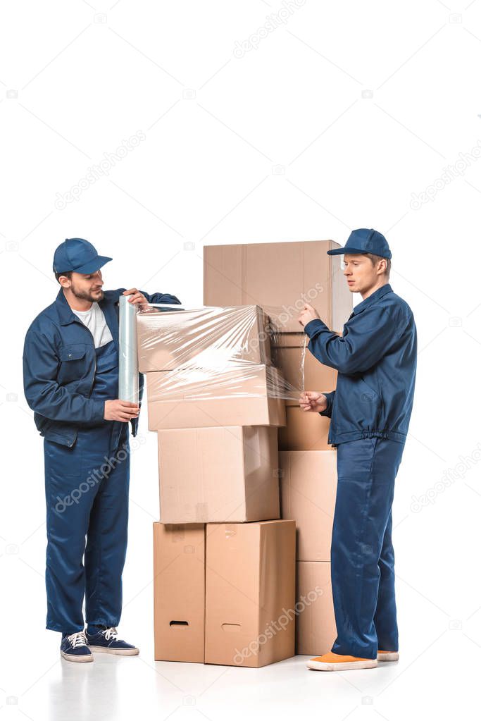 two movers wrapping cardboard boxes with roll of stretch film on white