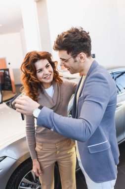 neşeli kıvırcık kadın ve araba showroom tutarak tuşları ile ayakta gözlük mutlu adam 