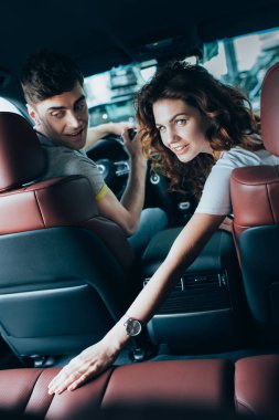 Otomobil mutlu adam yakın oturan çekici kıvırcık kadın seçici odak 