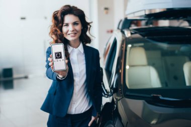 ekranda Uber uygulamasıyla akıllı telefon tutan güzel iş kadını seçici odak 