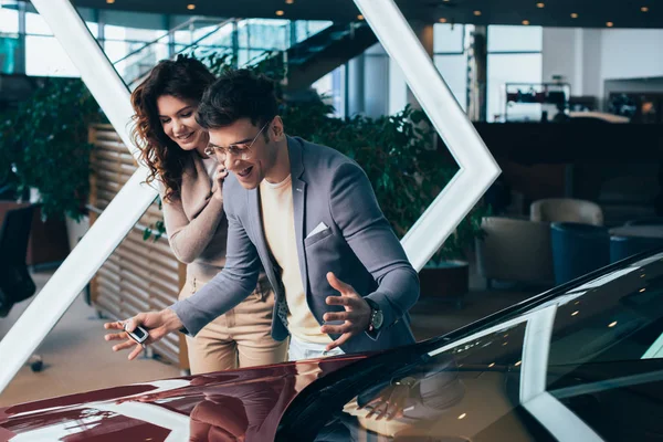 Opgewonden Man Kijken Naar Rode Auto Met Vrolijke Krullende Vrouw — Stockfoto