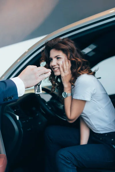裁剪视图的汽车经销商给钥匙兴奋成功的女人坐在车里 — 图库照片
