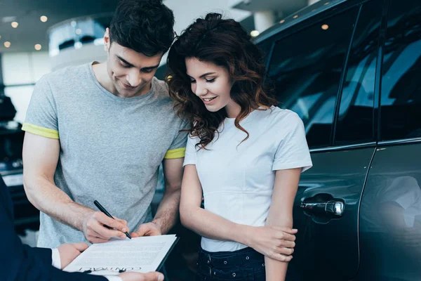 Recortado Vista Concesionario Coches Sujetando Portapapeles Mientras Hombre Feliz Firma — Foto de Stock