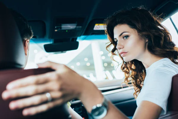 坐在汽车中的男人附近的卷曲的女人的选择性焦点 — 图库照片