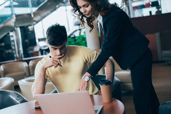 вдумчивый человек сидит за столом рядом с автомобильным дилером в автосалоне
