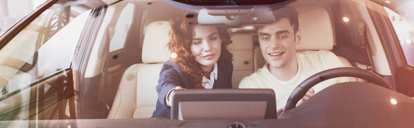 панорамный снимок красивого мужчины и привлекательного автодилера, сидящего в новой машине
