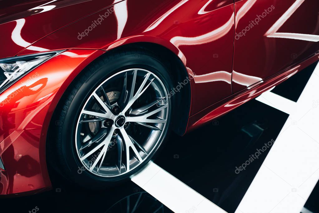 shiny new red automobile with metallic wheel in car showroom 