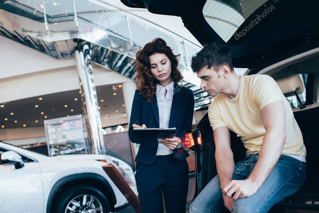 bell'uomo guardando concessionario di auto scrivere negli appunti