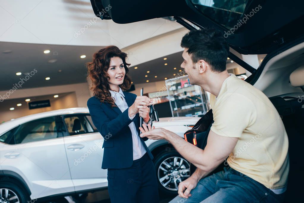 fuoco selettivo del cliente felice che prende le chiavi dell'automobile dal commerciante attraente dell'automobile