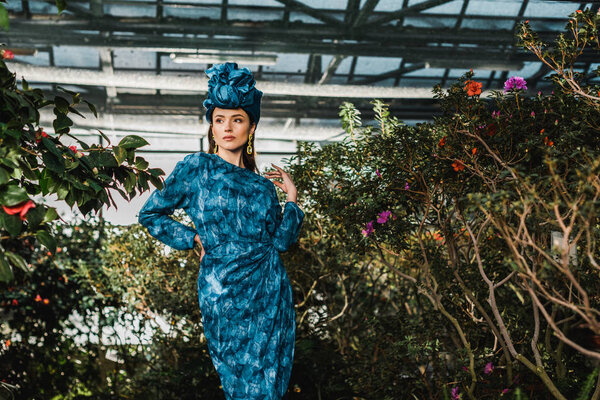 Gorgeous young woman in blue dress in turban in orangery