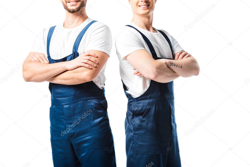 cropped view of two smiling movers in uniform with arms crossed isolated on white
