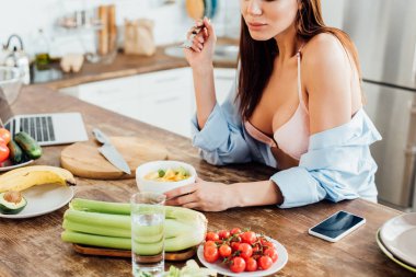 Sutyen ve gömlek mutfakta meyve salatası yeme seksi kız kırpılmış görünümü