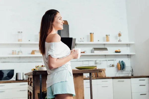 Vista Lateral Una Joven Sonriente Sosteniendo Una Taza Café Cocina — Foto de Stock