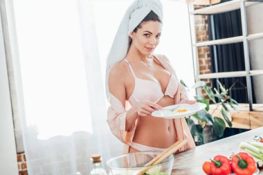 Kızarmış yumurta ile baş tutan tabak üzerinde havlu ile iç çamaşırı seksi kız