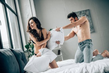 neşeli esmer kız yatakta kaslı erkek arkadaşı ile mücadele yastık sahip siyah iç çamaşırı 