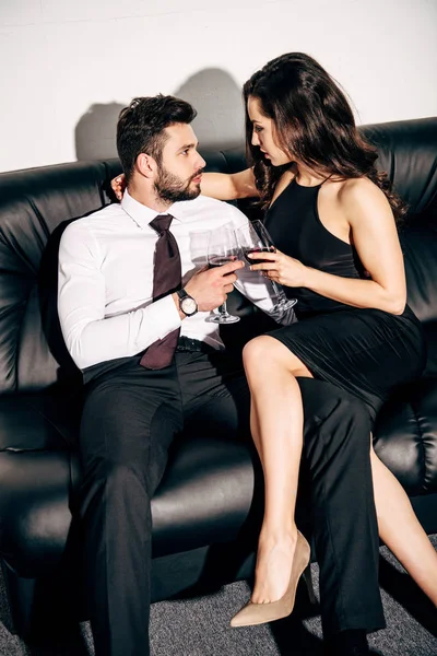 Homem Bonito Mulher Atraente Vestido Preto Sentado Sofá Segurando Copos — Fotografia de Stock