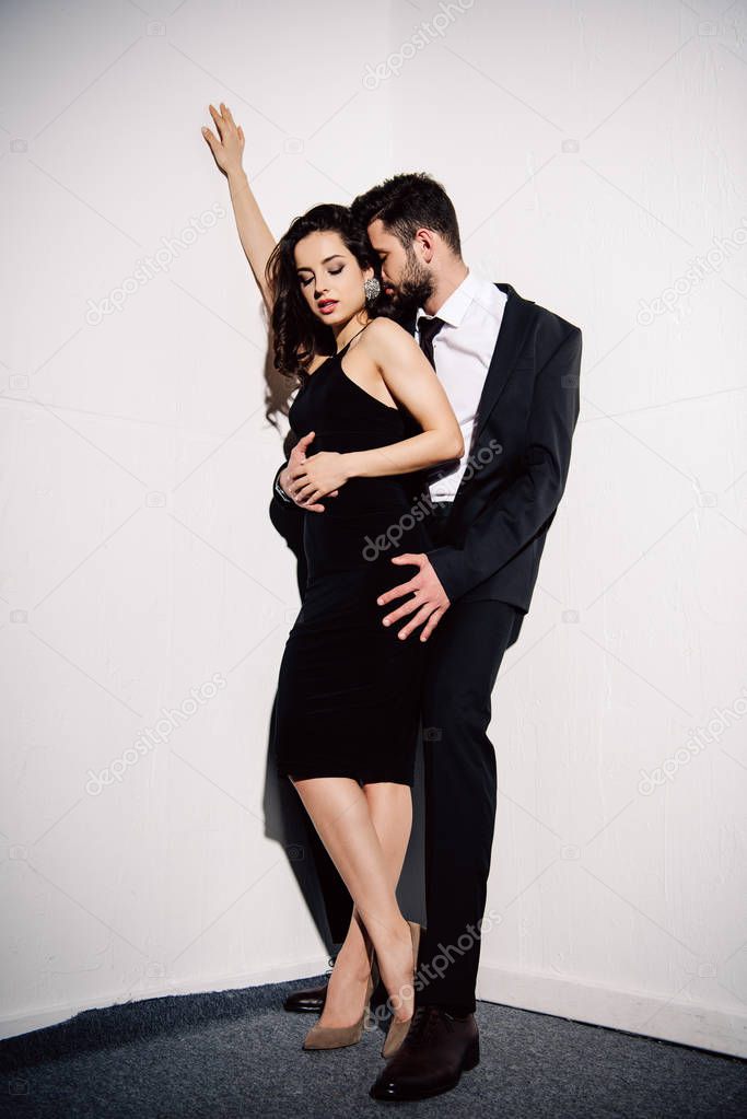 attractive brunette girl standing with handsome man near white wall