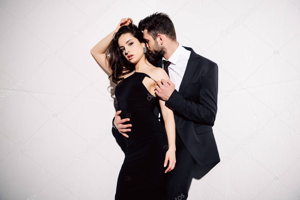 brunette woman in black dress standing with man on white
