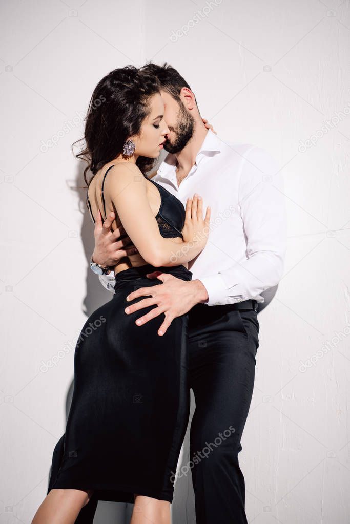 beautiful woman in black dress standing with bearded man on white 