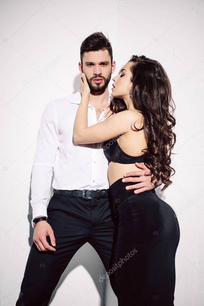 beautiful woman in black bra touching handsome man on white 