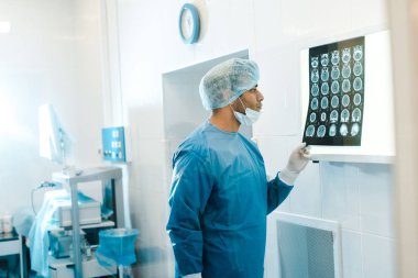 Klinikte x-ışını tutan üniforma ve tıbbi maske yakışıklı doktor yan görünümü 