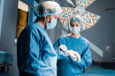 hemşire üniforma ve tıbbi maske Doktor elinde lateks eldiven koyarak 