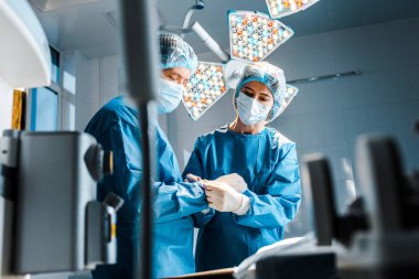 üniforma ve tıbbi maske hemşirenin seçici odak Doktor elinde lateks eldiven koyarak 