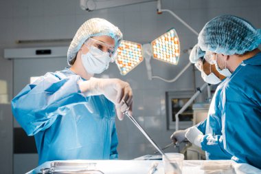 Doktorlar üniforma ve tıbbi kap tutma ekipmanında operasyon ve hemşire yapıyor 
