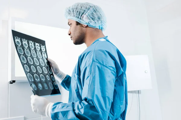 handsome doctor in uniform and medical cap holding x-ray in clinic