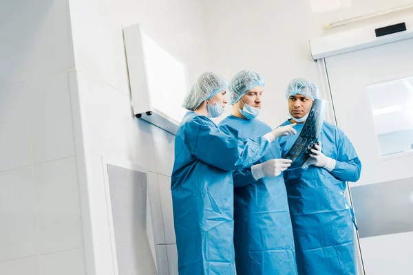 Médicos Bonitos Atraentes Uniformes Máscaras Médicas Apontando Com Dedo Para — Fotografia de Stock